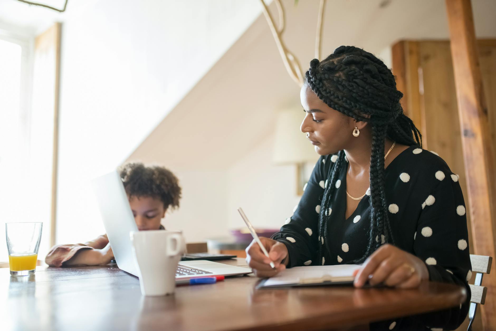 young black mother working on laptop with child sitting near